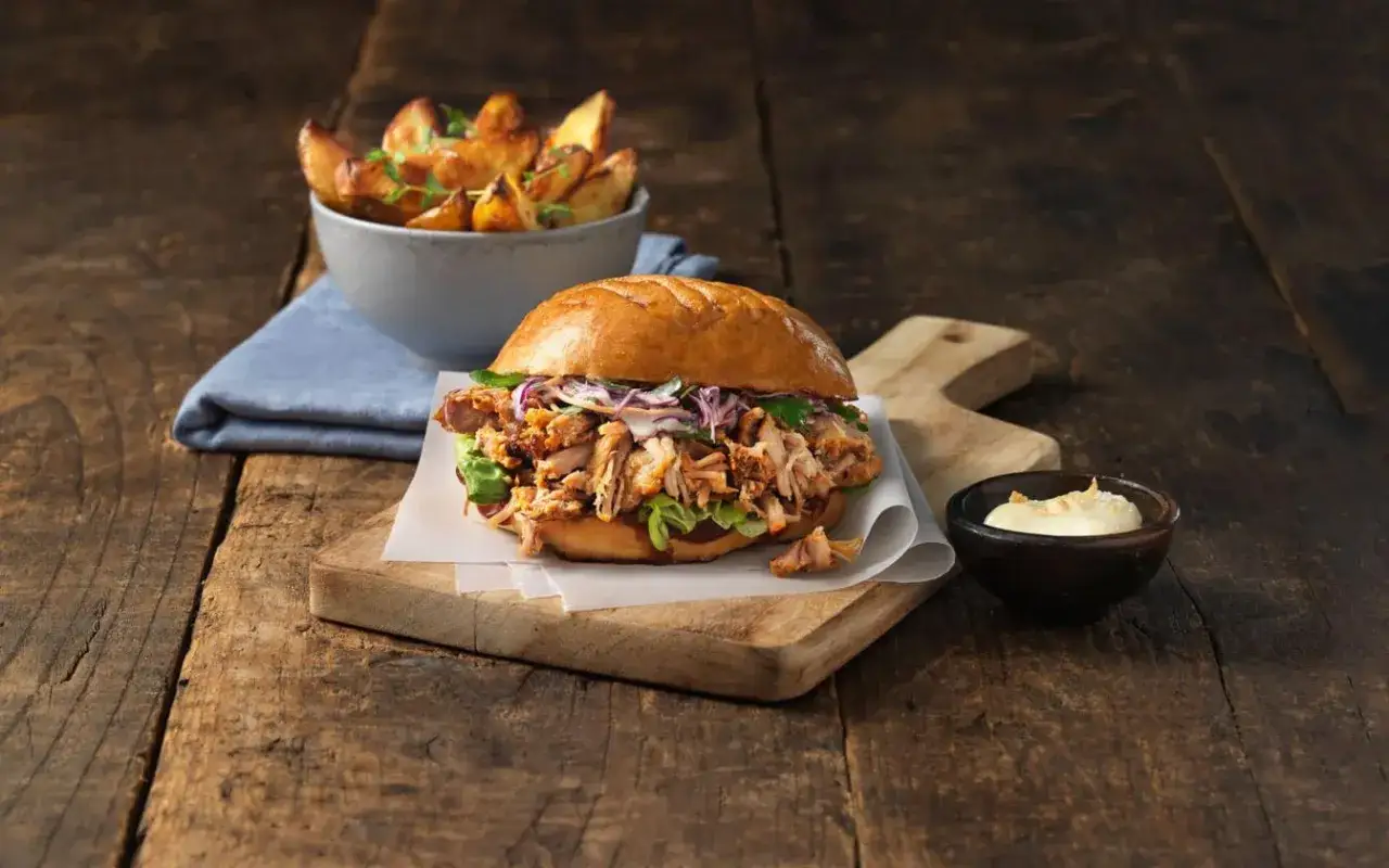 En saftig pulled pork-burgare med krispig coleslaw och en god s&aring;s till pulled pork. Serveras med ugnsrostade potatisklyftor.