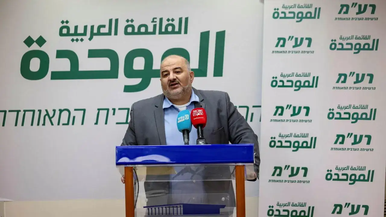 Mann spricht bei einer Pressekonferenz im Hintergrund mit arabischer Schrift. Die arabische Partei