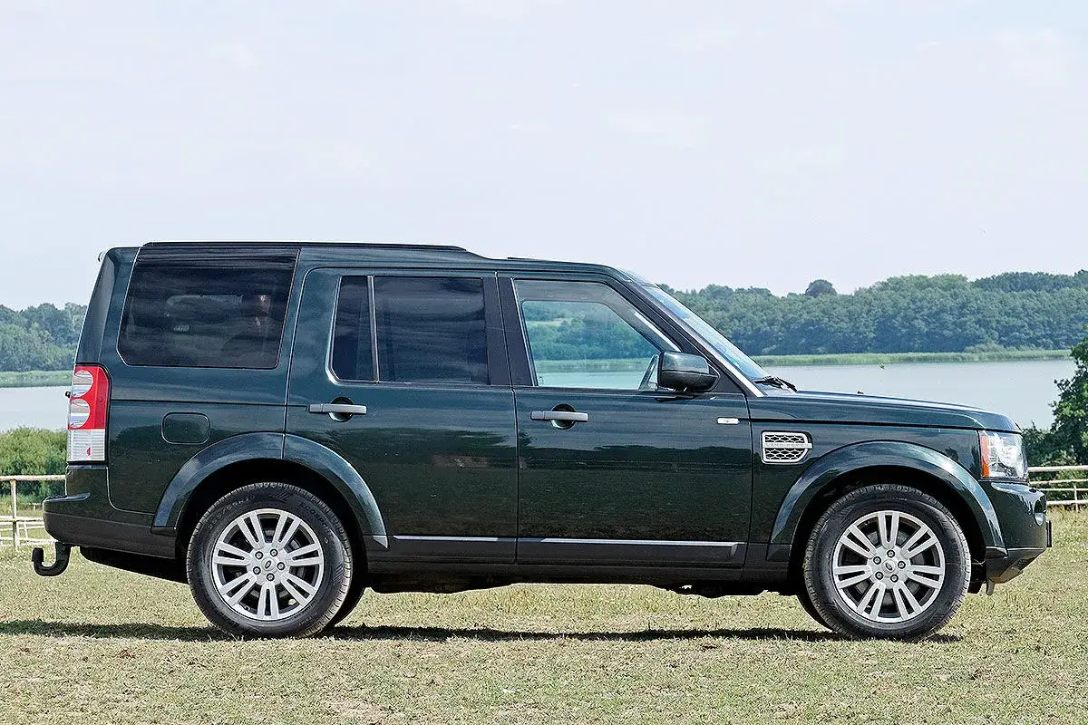 Dunkelgr&uuml;ner Land Rover Discovery 4 im Profil, mit Blick auf die Landschaft. Bekannt f&uuml;r seine Gel&auml;ndetauglichkeit, aber auch f&uuml;r seine Land Rover Discovery 4 Schwachstellen.