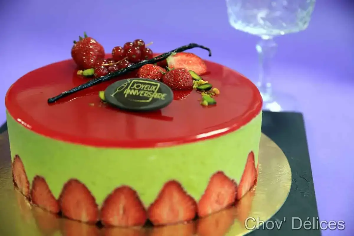 Gâteau d'anniversaire vert pistache avec un glaçage fraise brillant, décoré de fruits rouges et d'une inscription