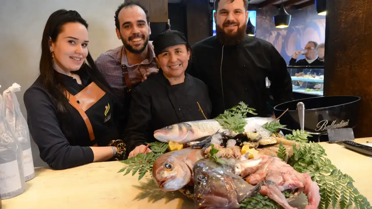 El equipo de la brasserie 1885 sonríe junto a una fresca exhibición de mariscos y pescados.