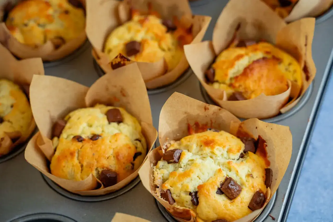 Frisch gebackene Quark Muffins mit Schokostückchen in braunen Papierförmchen, bereit zum Genießen.