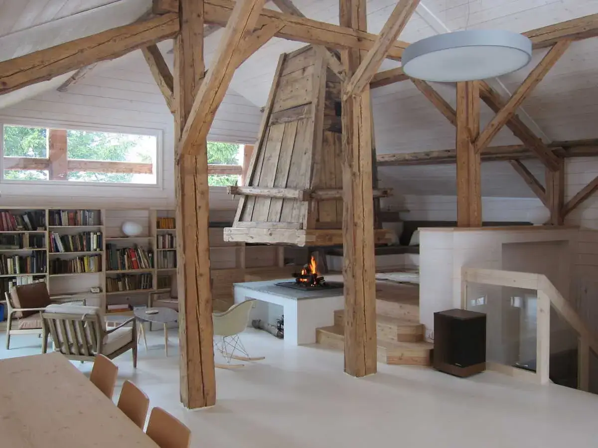 Ambiance chaleureuse dans un **intérieur ferme rénovée moderne**. Poutres apparentes, cheminée crépitante, et coin lecture cosy.