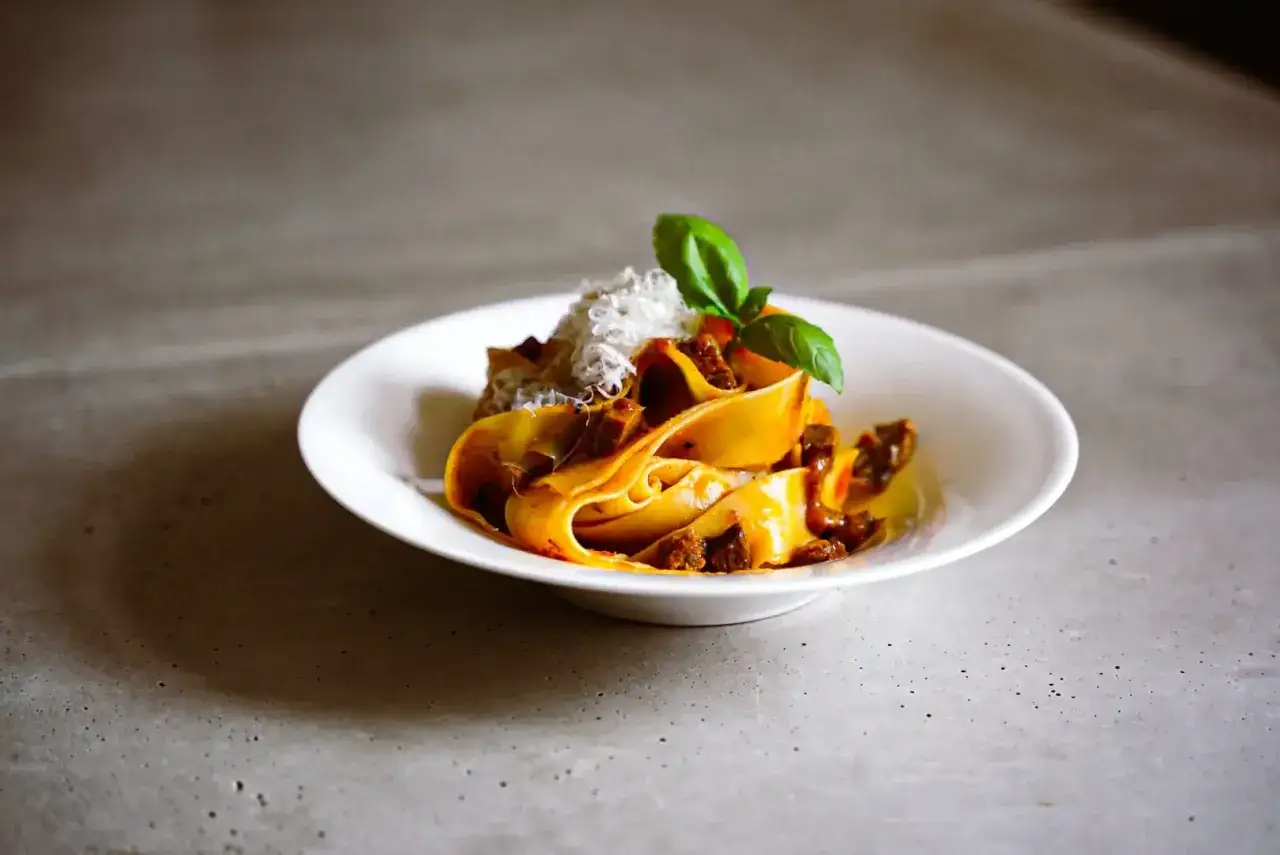 Breite Bandnudeln mit herzhaftem Rindfleisch, garniert mit Parmesan und Basilikum – ein klassisches italienisches Gericht.
