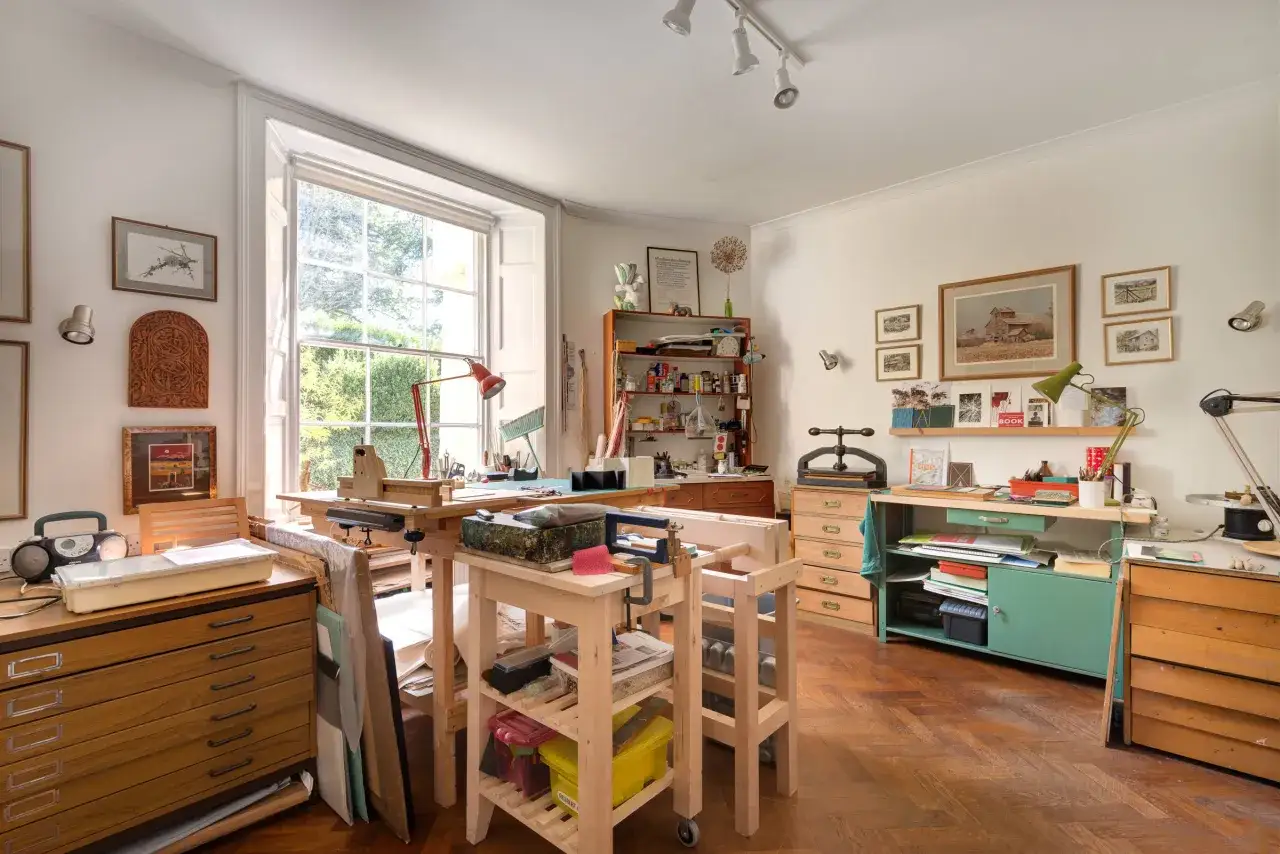 Atelier d'artiste lumineux, rempli d'outils et de matériaux. Le style d'art peinture est présent dans les œuvres accrochées aux murs.