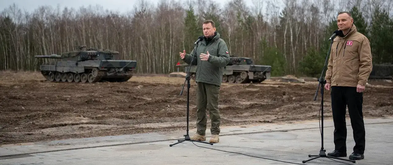 Prezydent Duda i minister obrony przemawiają na tle czołgów Leopard. To symbol wsparcia dla Ukrainy, gdzie polskie wojsko jest gotowe do pomocy.