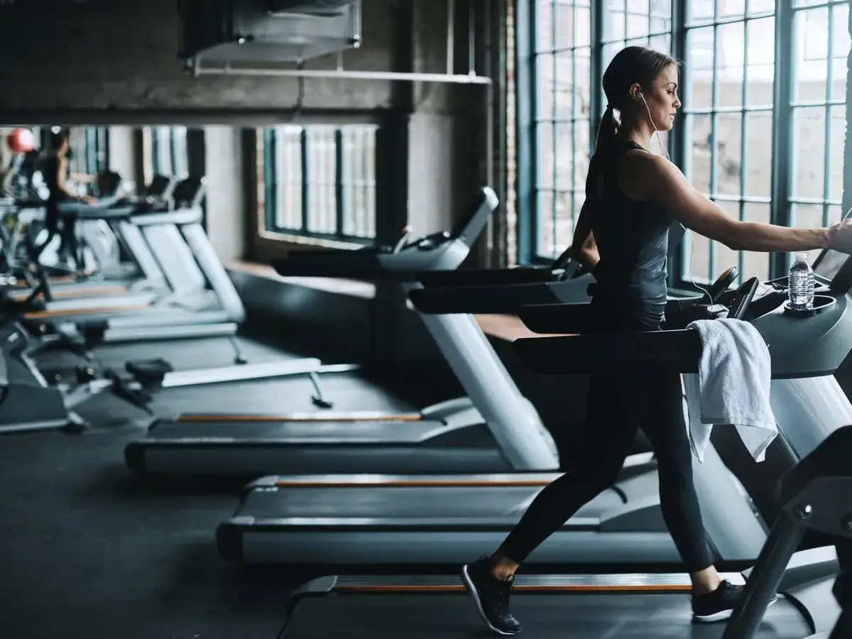 Donna corre su un tapis roulant in palestra. La corsa indoor &egrave; un ottimo modo per mantenersi in forma.