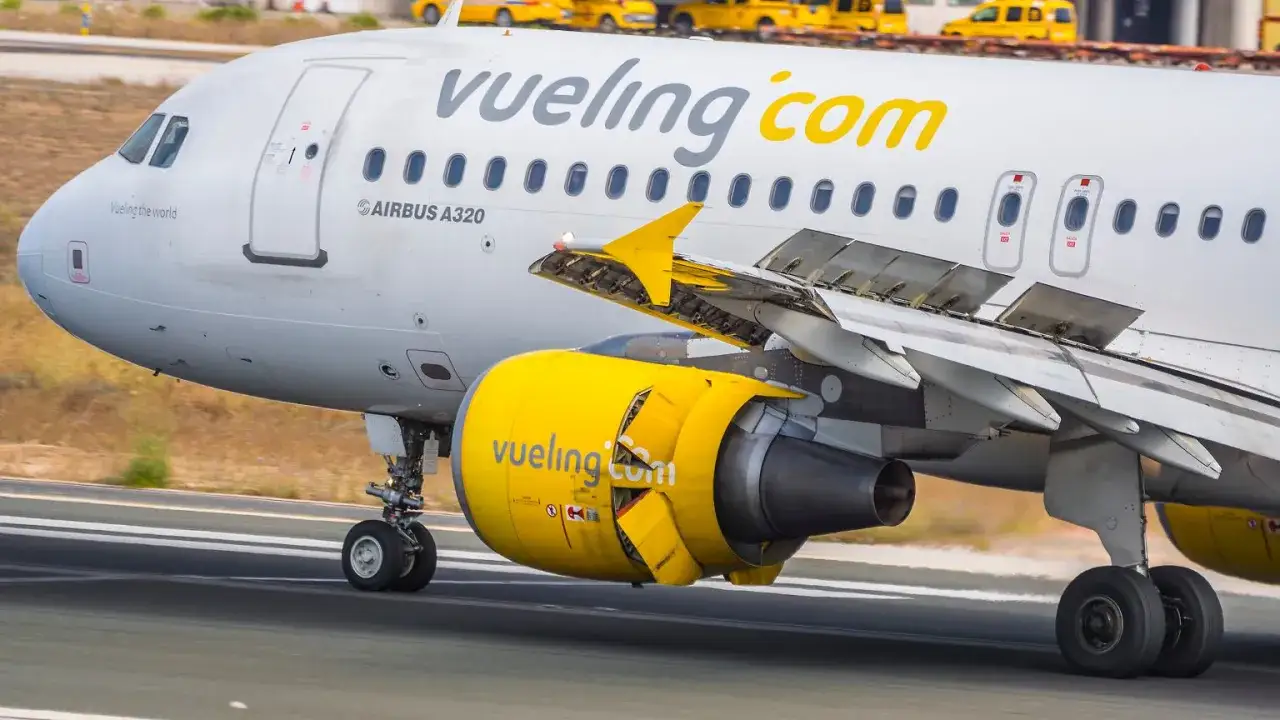 Samolot hiszpańskich linii lotniczych Vueling z żółtym silnikiem na pasie startowym.