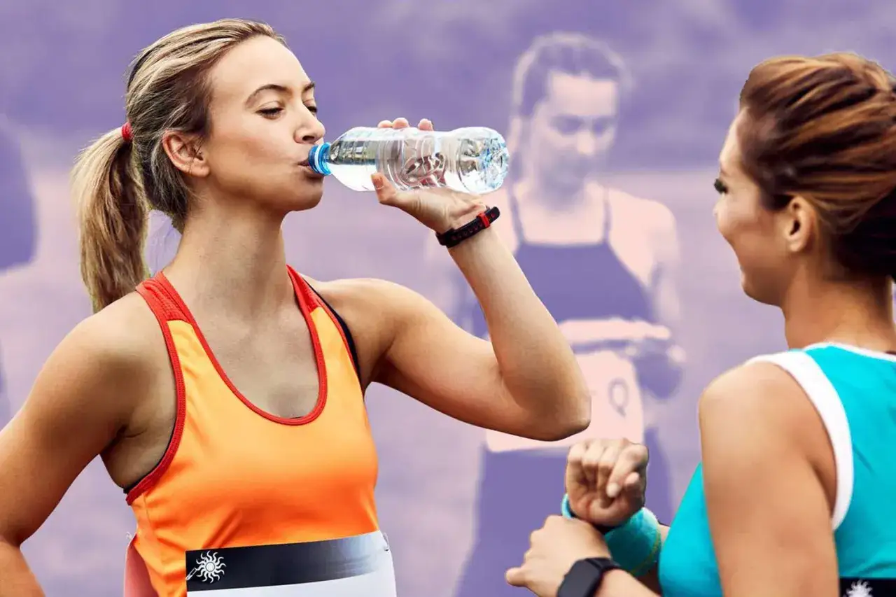 Deux coureuses se ravitaillent. L'une boit de l'eau, l'autre lui tend la main. L'alimentation sport endurance est essentielle pour la performance.