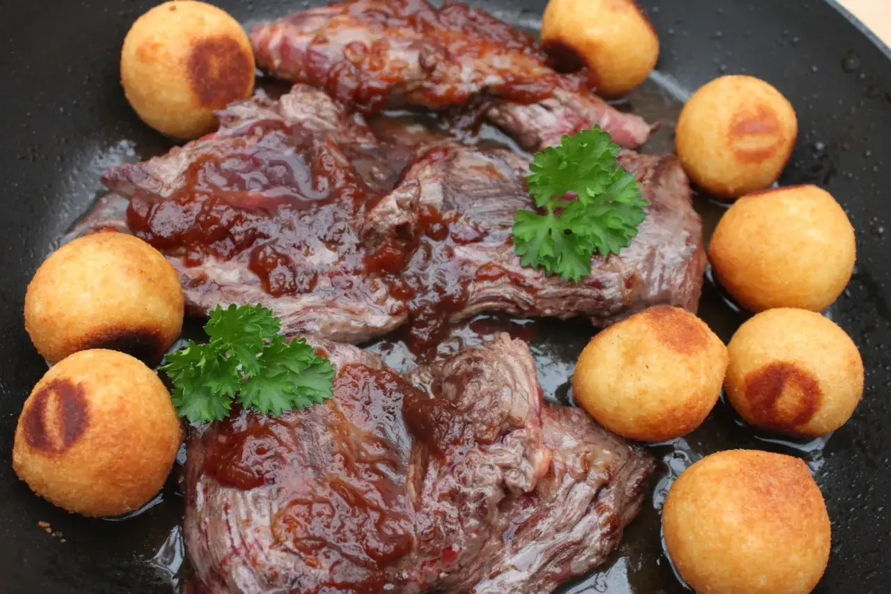 Délicieux onglet à l'échalote, servi avec des pommes dauphine dorées et garni de persil frais. Un plat savoureux prêt à être dégusté.