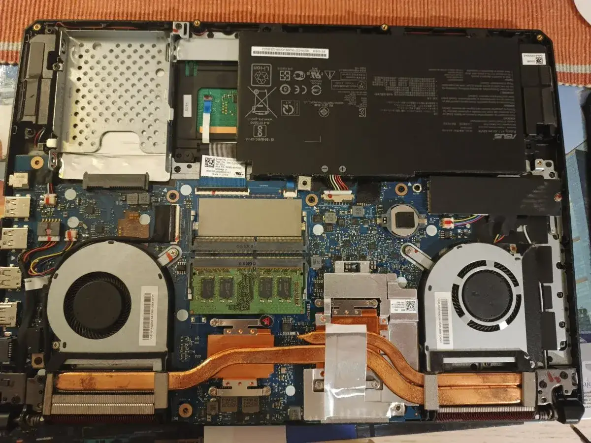 Wnętrze laptopa z widocznym **ram w laptopie**, baterią, wentylatorami i płytą główną.