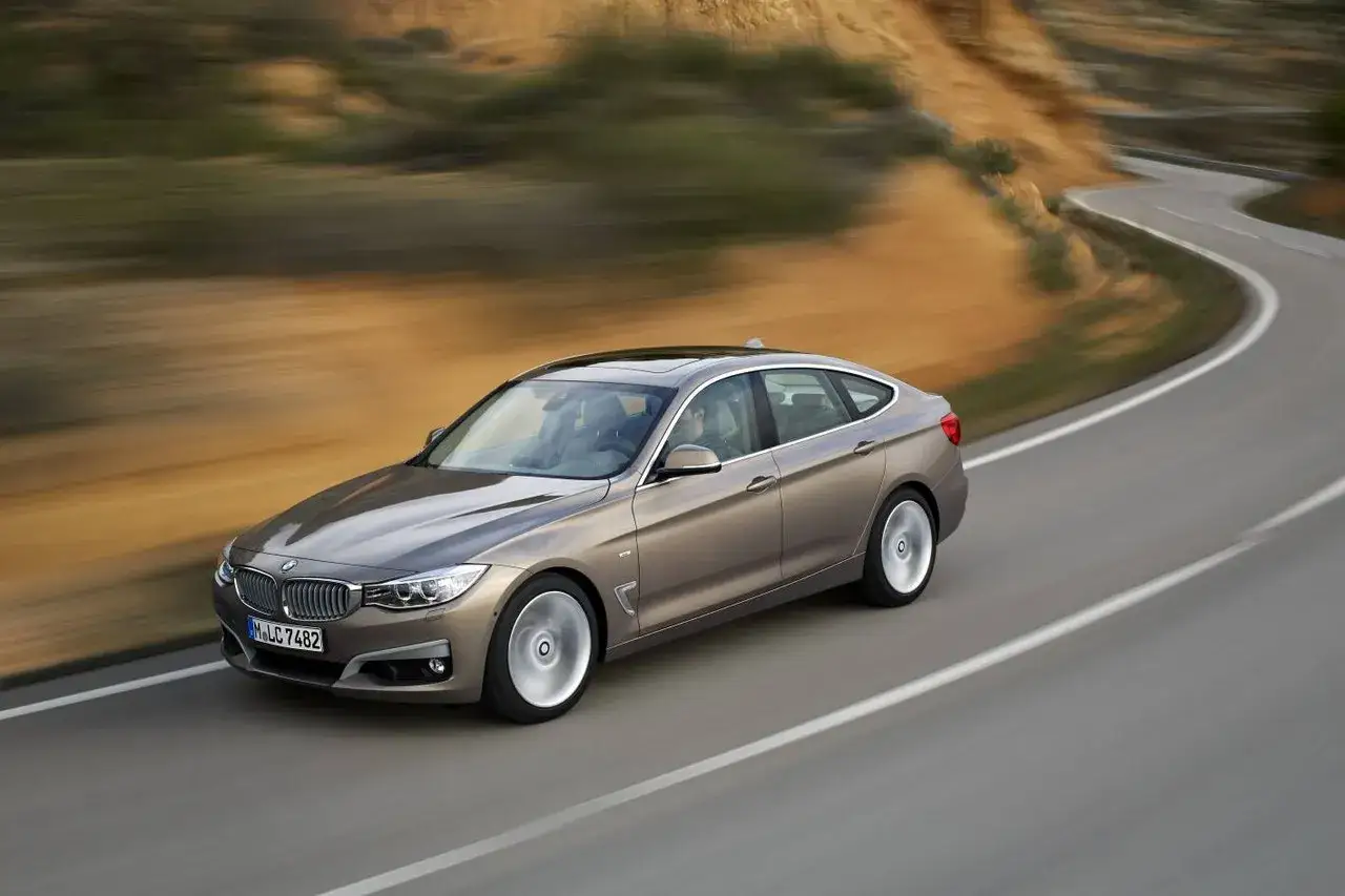 Brązowe BMW F34 na krętej drodze, w tle pustynny krajobraz.