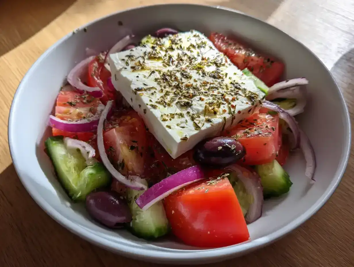 En fr&auml;sch grekisk sallad med fetaost, tomater, gurka, r&ouml;dl&ouml;k och oliver, toppad med &ouml;rter.