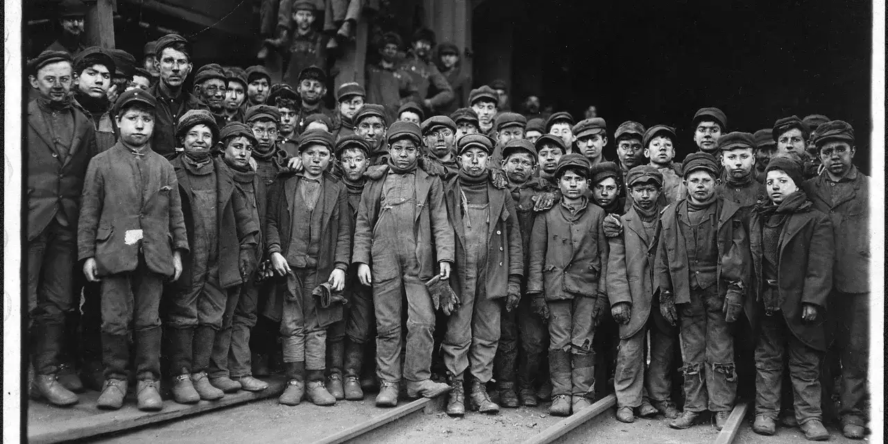 En grupp pojkar, klädda i slitna kläder, vittnar om barnarbete under den industriella revolutionen.