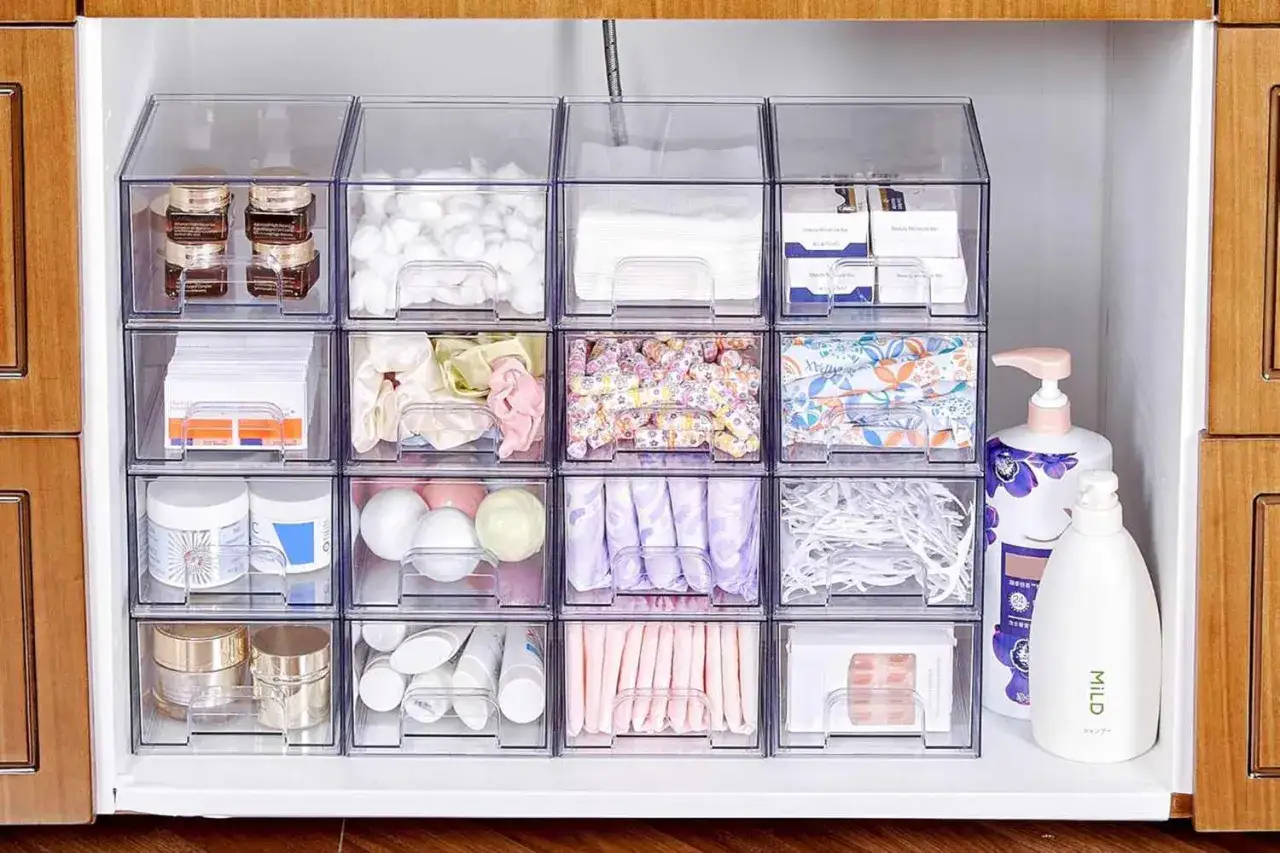 Clear bins neatly organize a medicine cabinet, showcasing cotton balls, skincare, and personal care items. This image offers inspiration on how to organize medicine cabinet contents for easy access.