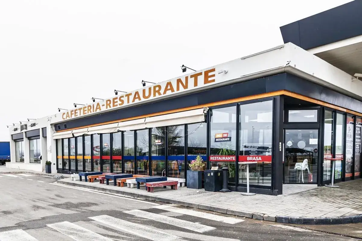 Cafetería-restaurante en la carretera, ideal para comer cerca de Zaragoza. Mesas y bancos de colores esperan fuera.