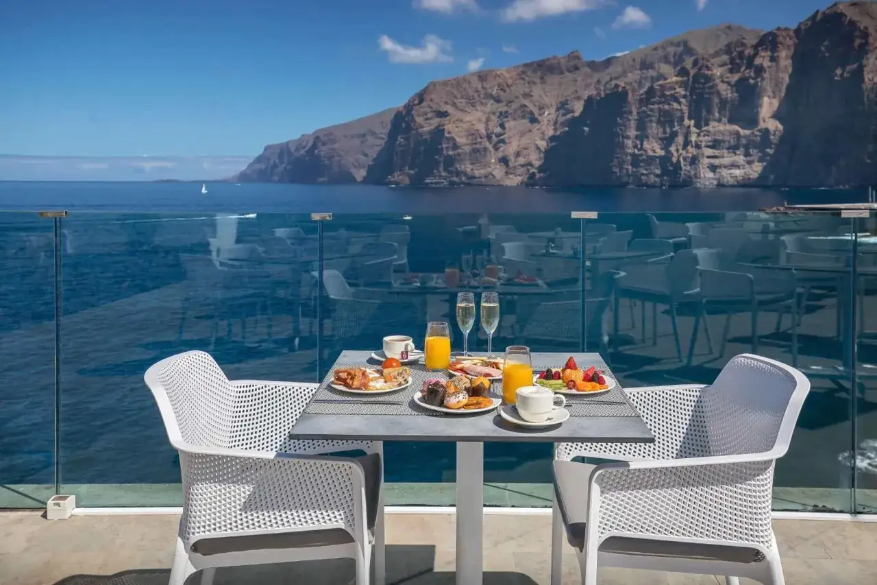 Desayuno con vistas a tui blue los gigantes. Fruta fresca, bollería y cava esperan en una mesa junto al mar.