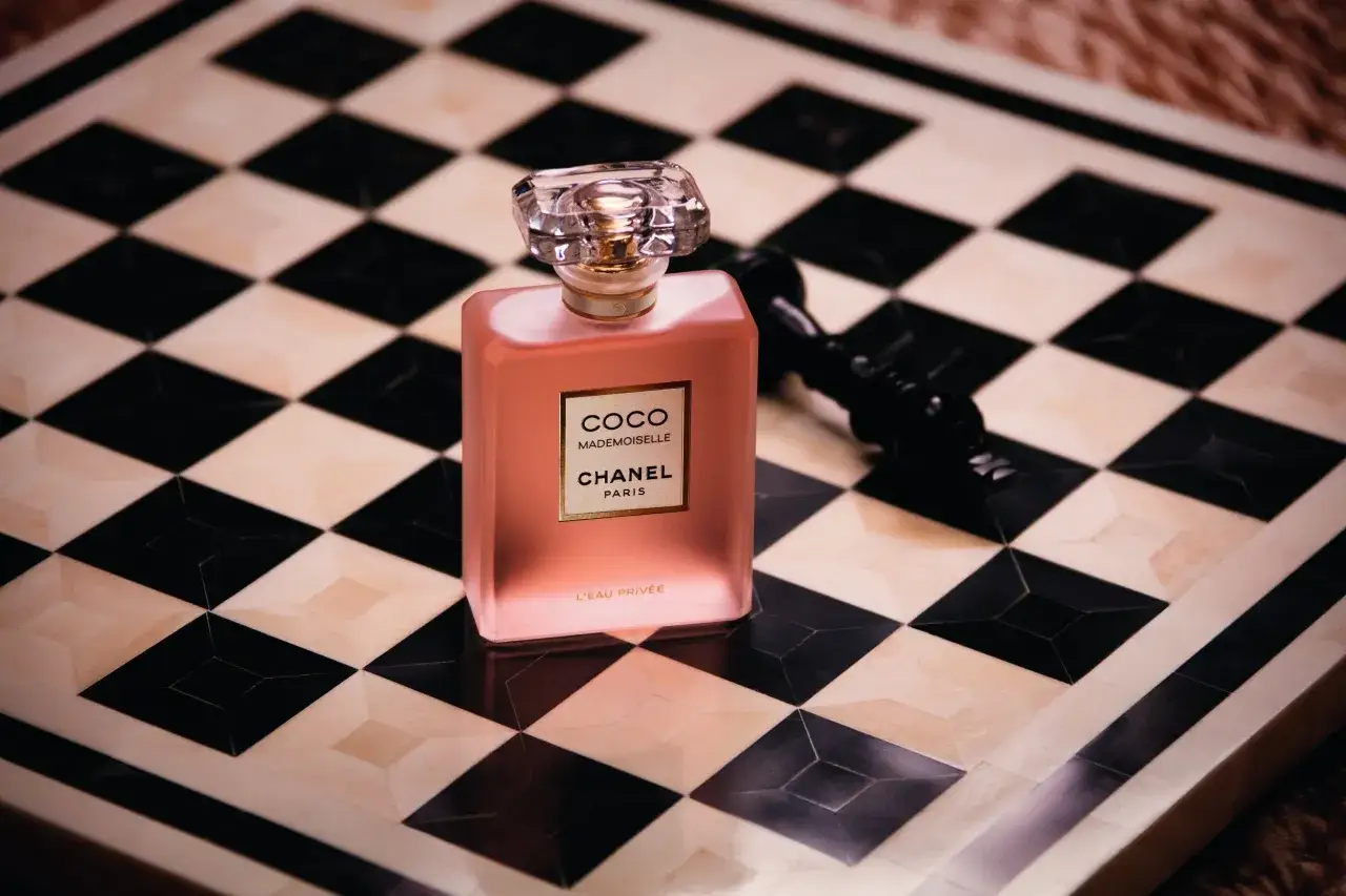 Różowa butelka Chanel Coco Mademoiselle L'Eau Privée na szachownicy.