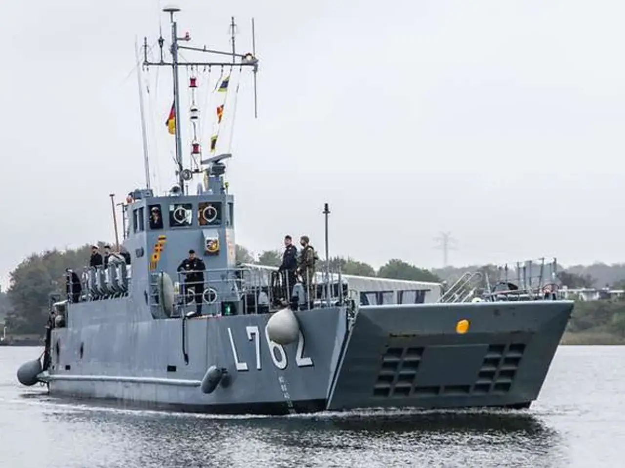 Graues Milit&auml;rschiff L762 f&auml;hrt auf dem Wasser. An seinem Mast wehen bunte Flaggen, die Schiffshorn Signale geben k&ouml;nnten.