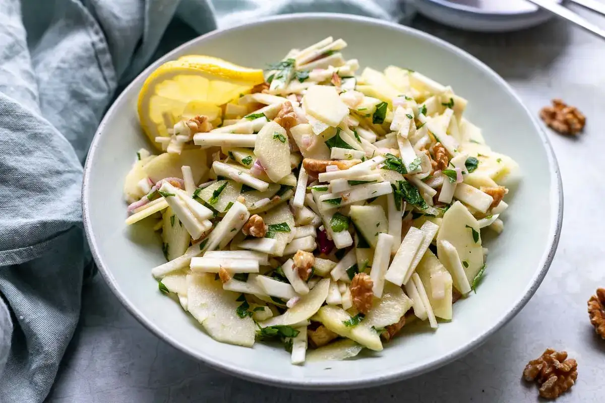 Frischer Selleriesalat mit Äpfeln und Walnüssen, garniert mit einer Zitronenspalte. Ein leichtes und gesundes selleriesalat rezept.