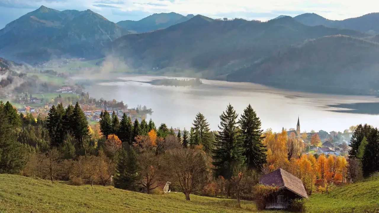 Herbstliche Szene mit See und Bergen. Ein kleines Haus steht auf der unteren Firstalm, umgeben von bunten B&auml;umen.