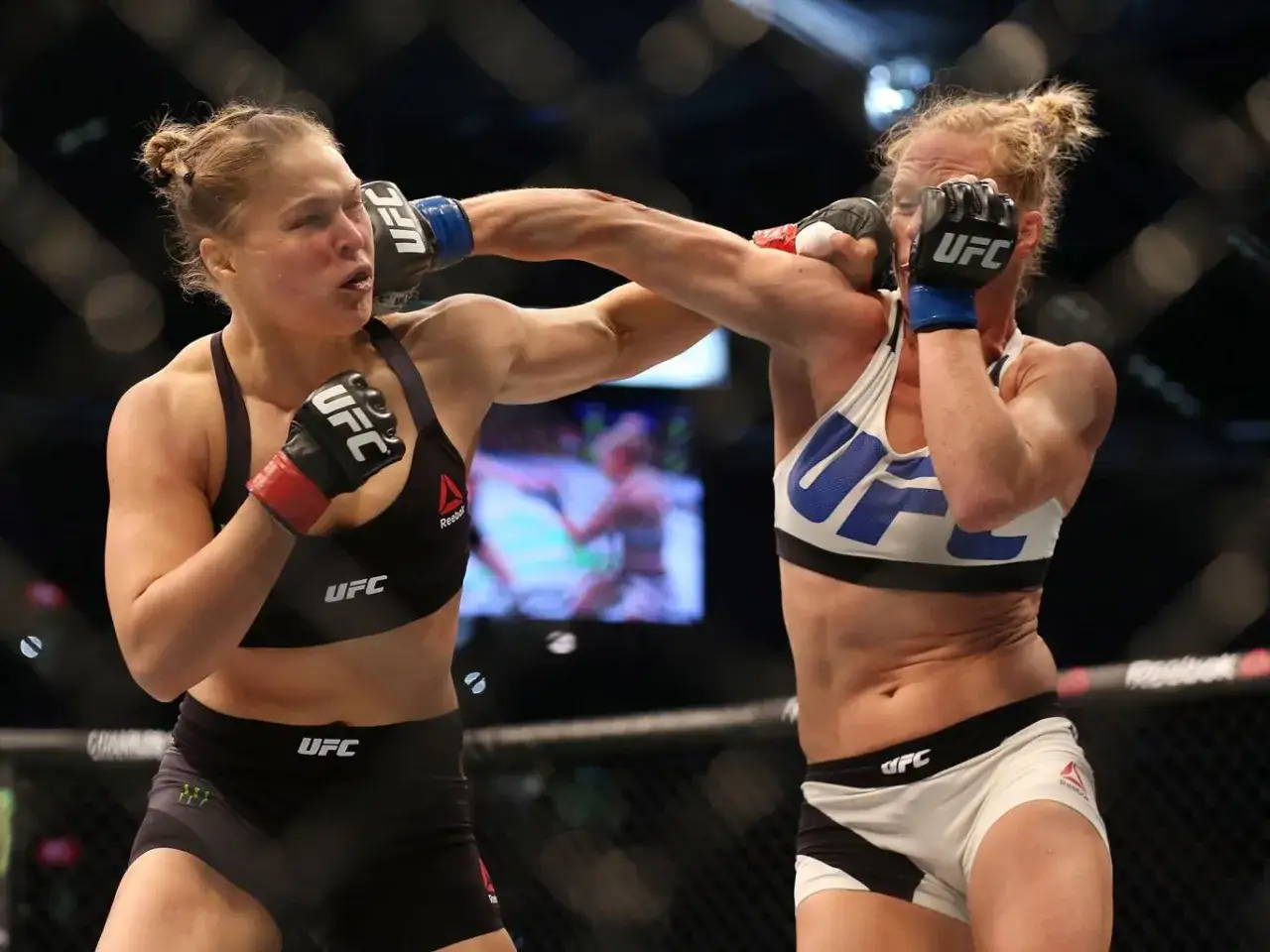 Two female UFC fighters exchange blows. One lands a powerful overhand punch, her opponent bracing for impact.