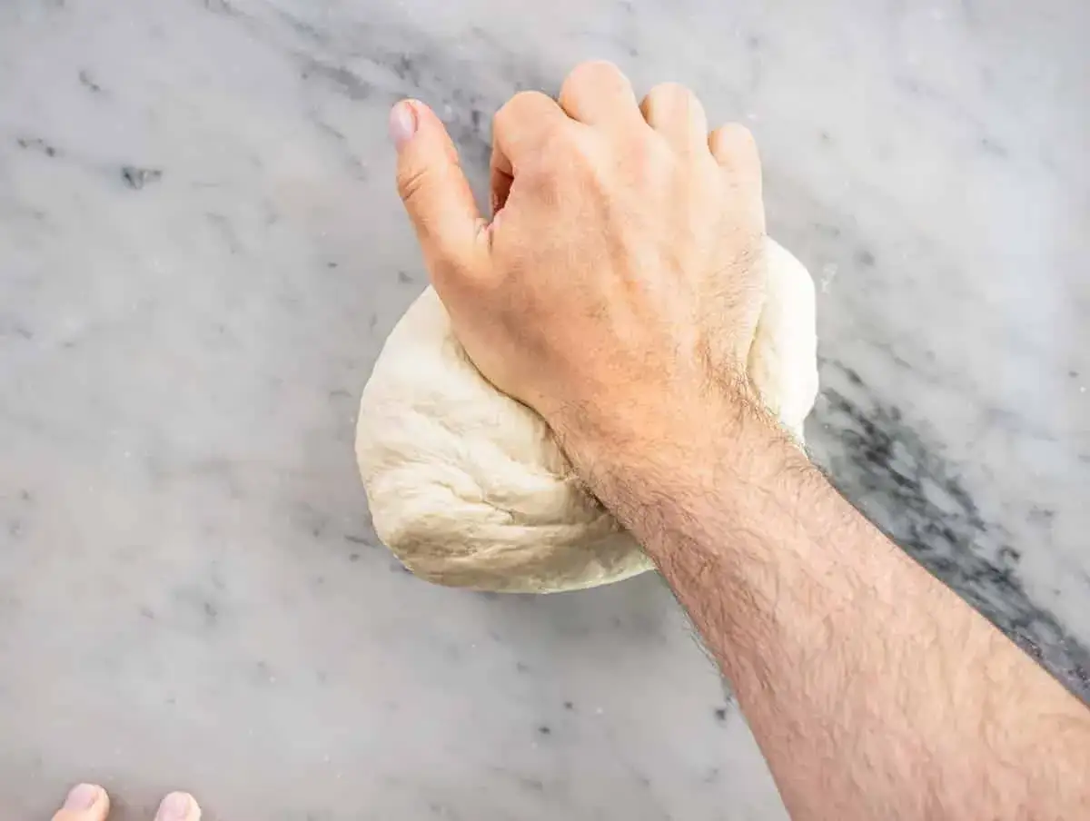 Hand knådar pizzadeg på marmorbänk. Perfekt för att baka pizza samma dag.