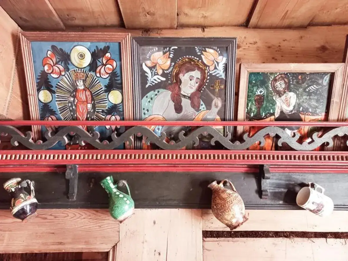Obrazy religijne i ceramiczne dzbanki na p&oacute;łce w muzeum powstania chochołowskiego.