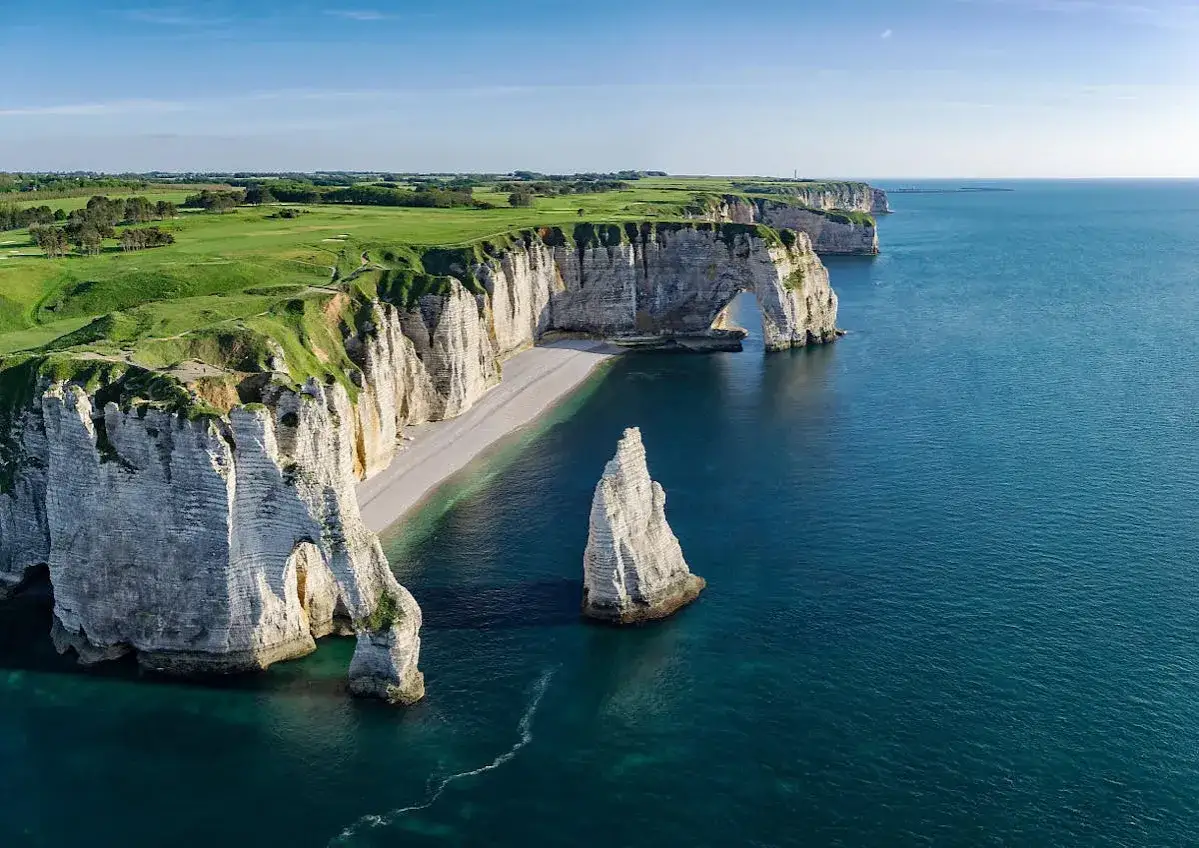 Falaises d'Étretat, un parcours de golf verdoyant surplombe la mer d'Émeraude. L'arche et l'aiguille rocheuse se dressent, témoins de gr 21 étapes.