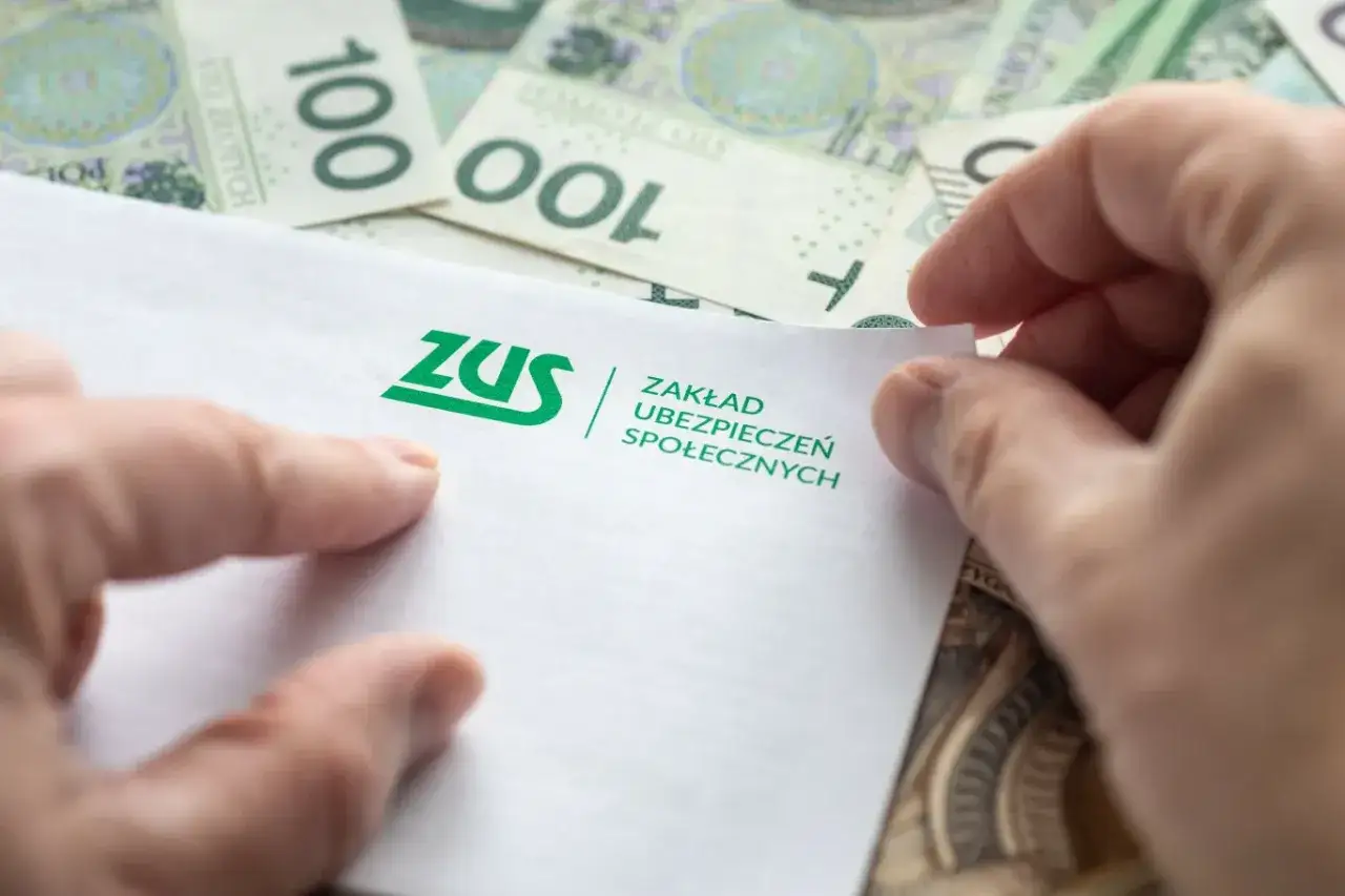 Dłonie trzymają dokument z logo ZUS. W tle polskie banknoty 100 zł. Sprawa dotyczy subkonta ZUS po zmarłym.