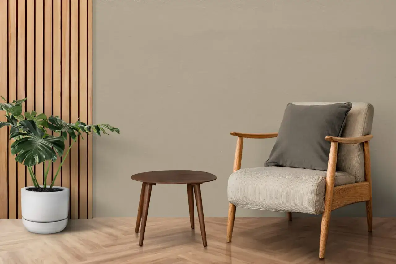 Wnętrze w odcieniu taupe jaki to kolor. Jasna sofa, drewniane akcenty i roślina tworzą przytulną aranżację.