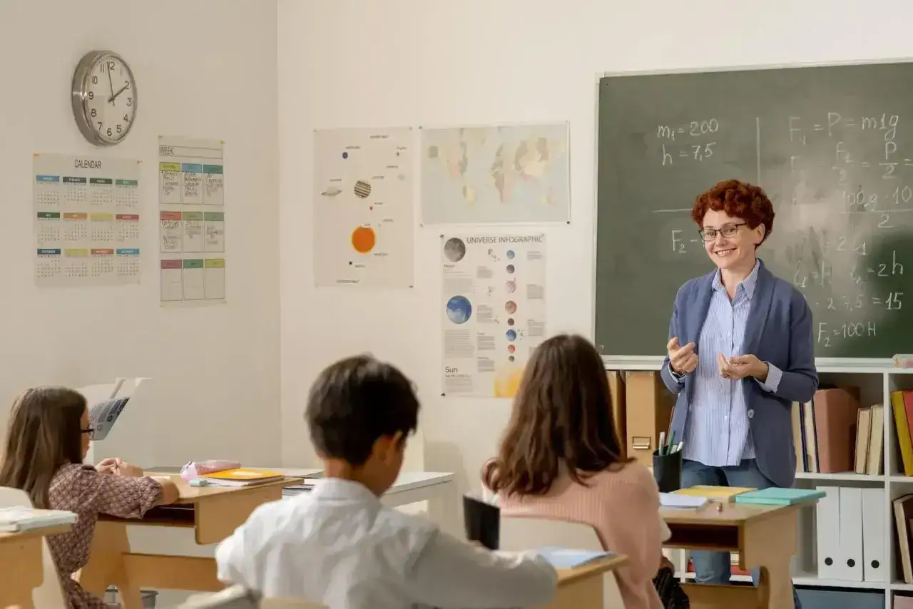 Nauczycielka tłumaczy zadanie z fizyki, a uczniowie słuchają. Czy to zapowiedź podwyżki dla nauczycieli? Najnowsze wiadomości wkrótce!