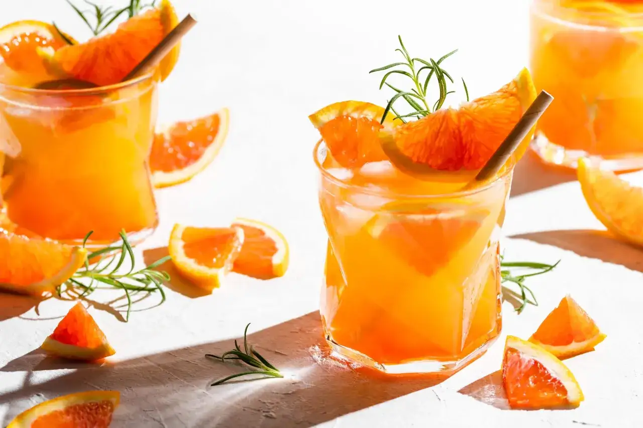 Erfrischender Aperitif mit Prosecco, Eis, Orangenscheiben und Rosmarin. Perfekt für einen sonnigen Nachmittag.