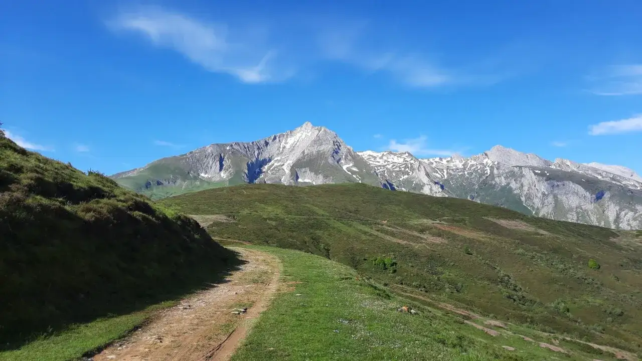 Sentier rocailleux menant au col du Soulor, avec des montagnes enneigées en arrière-plan sous un ciel bleu éclatant.