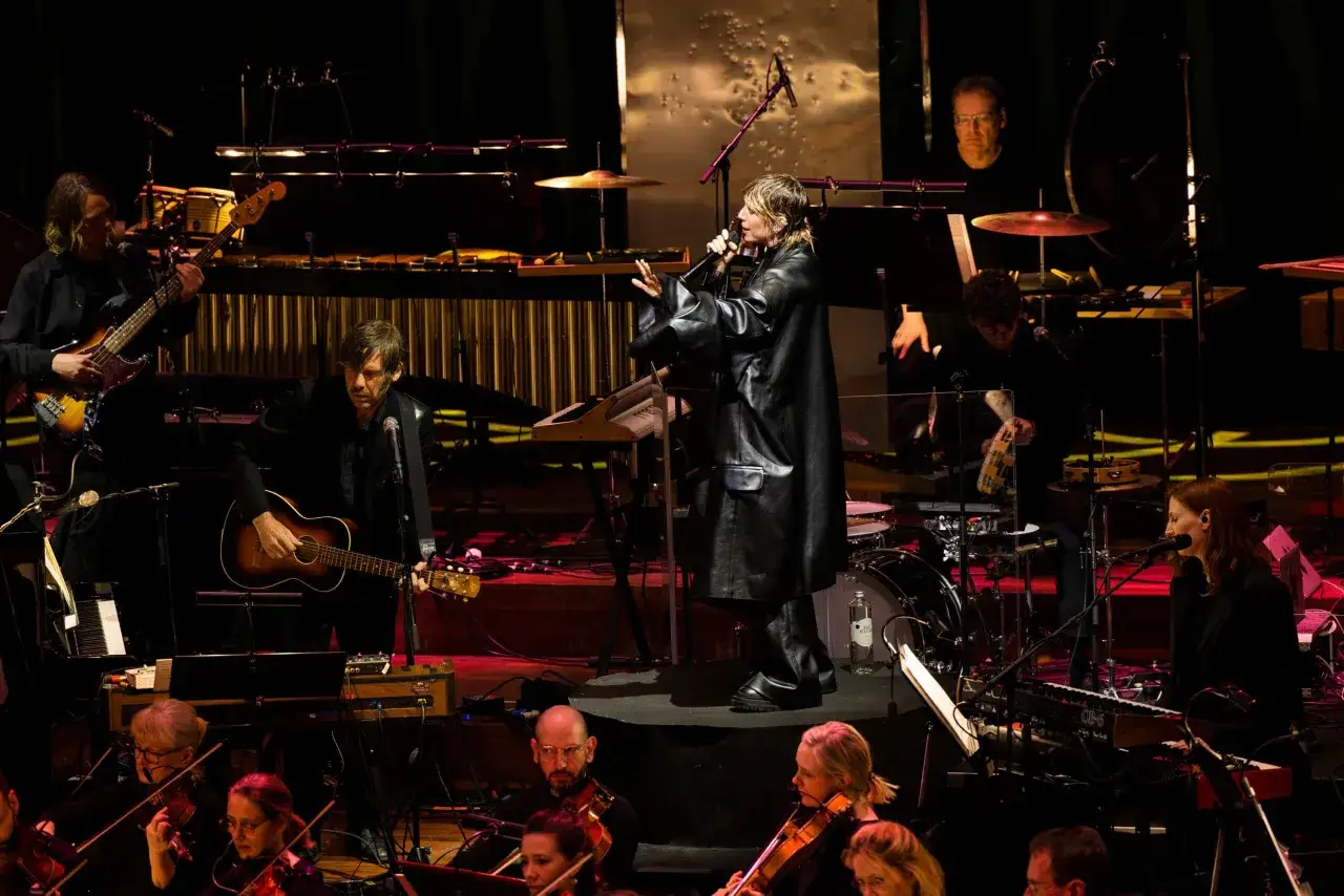 En artist uppträder på scenen med ett band och en orkester. En fantastisk kväll på en av Stockholms konsertlokaler.