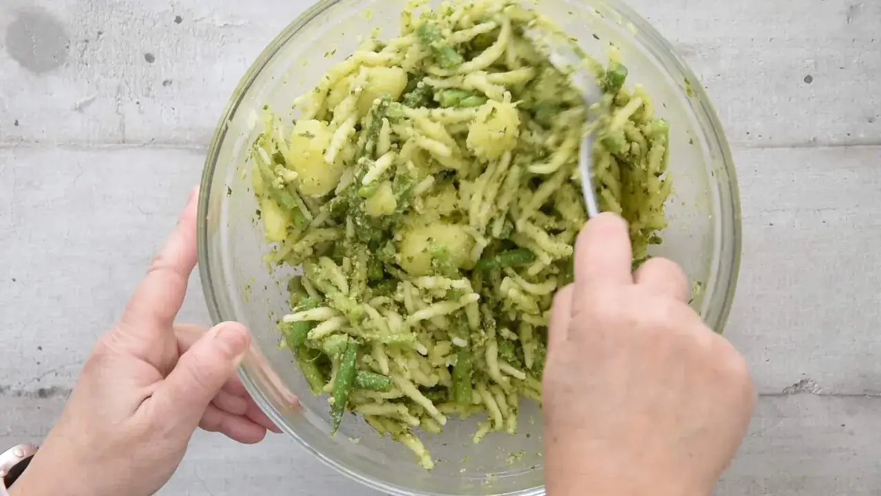 Un plat de p&acirc;tes italiennes avec des pommes de terre et des haricots verts, le tout enrob&eacute; d'une sauce verte.