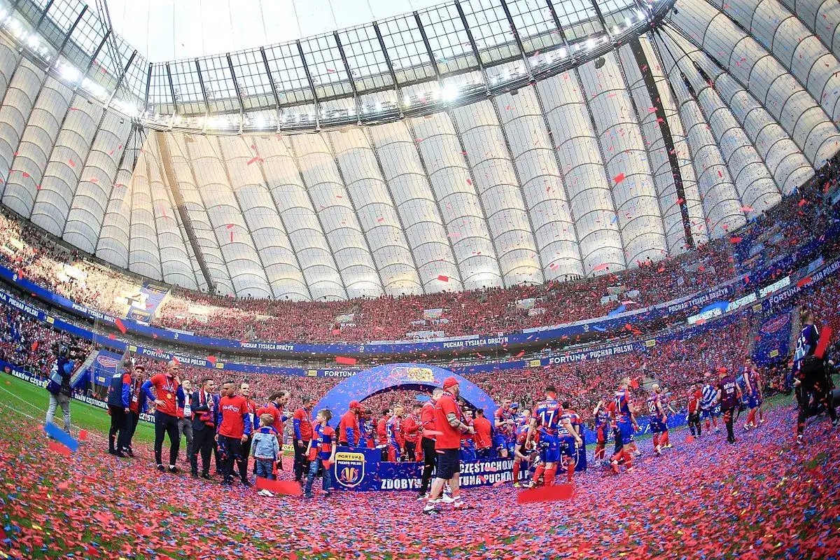 Piłkarze świętują zdobycie Fortuna Pucharu Polski na murawie stadionu, zasypani czerwonymi konfetti.