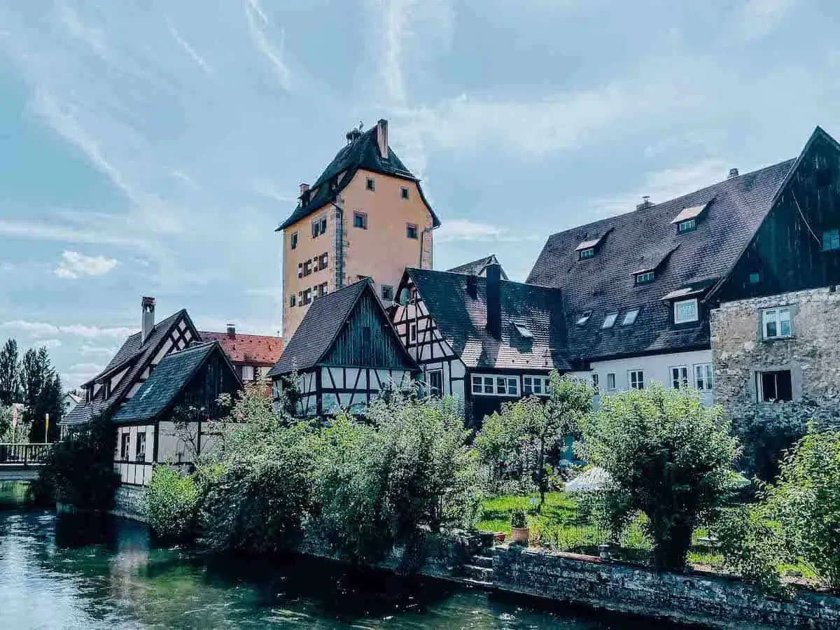 Fachwerkhäuser und ein hoher Turm säumen einen Fluss in Hersbruck, Bayern.