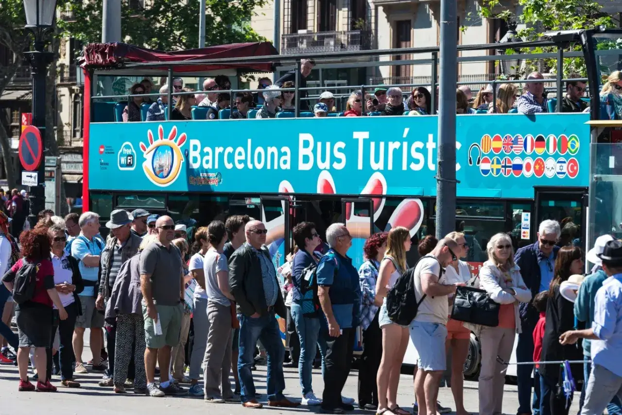 Tłum turystów czeka na autobus Barcelona Bus Turístic. Czy w Barcelonie jest bezpiecznie? Turyści wyglądają na zrelaksowanych, co sugeruje, że tak.