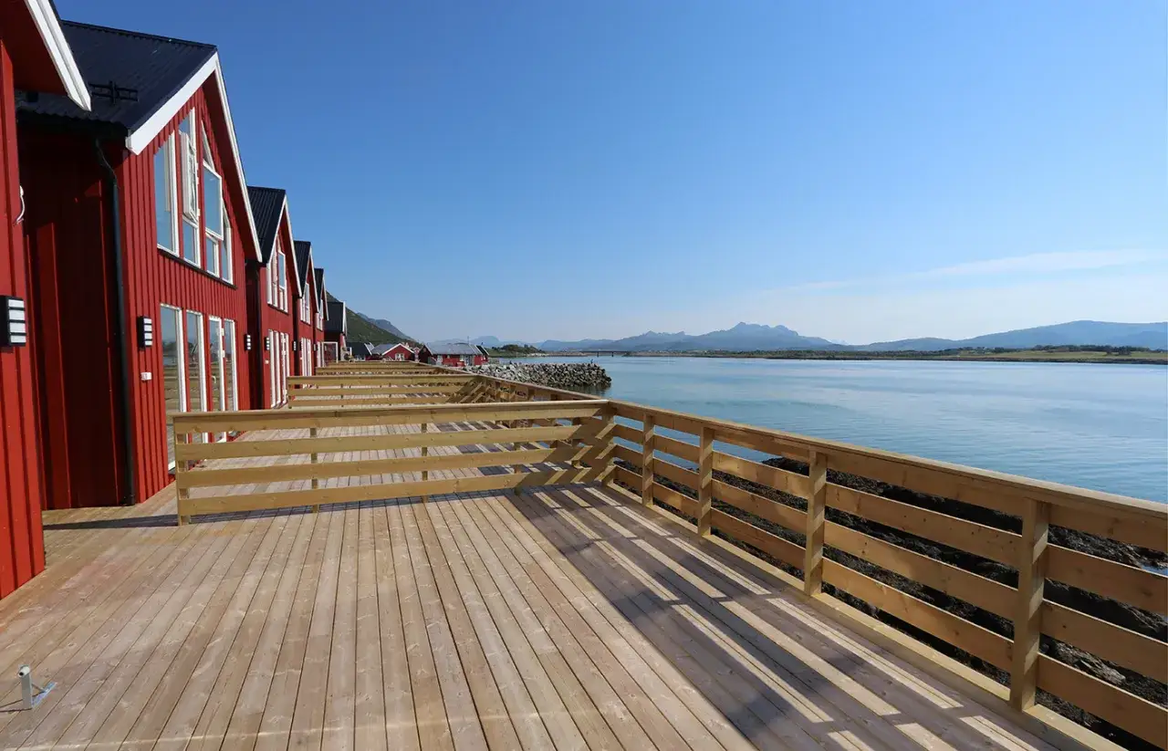 Röda stugor med altan vid vattnet, perfekt boende i Lofoten.