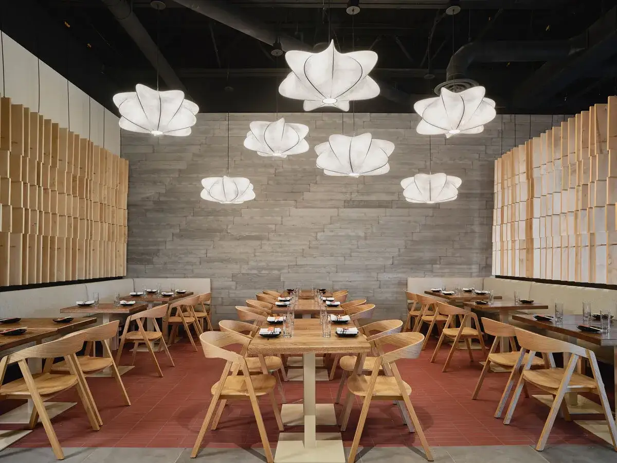 Modernes Interieur eines Restaurants in Berlin, bereit f&uuml;r Sushi-G&auml;ste. Helle Holzm&ouml;bel und einzigartige Lampen schaffen eine einladende Atmosph&auml;re.