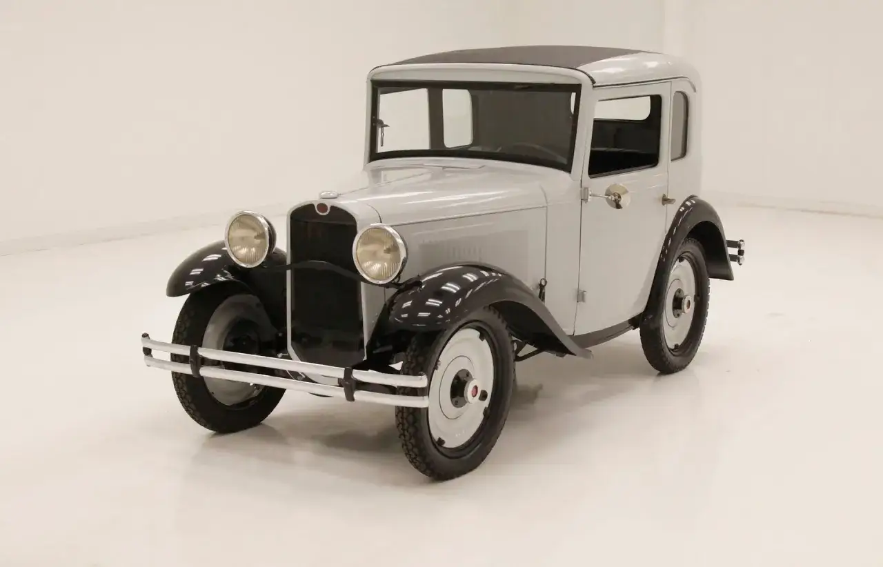 En ljusgrå Austin-bilmodell från 1930-talet med svarta skärmar och tak.