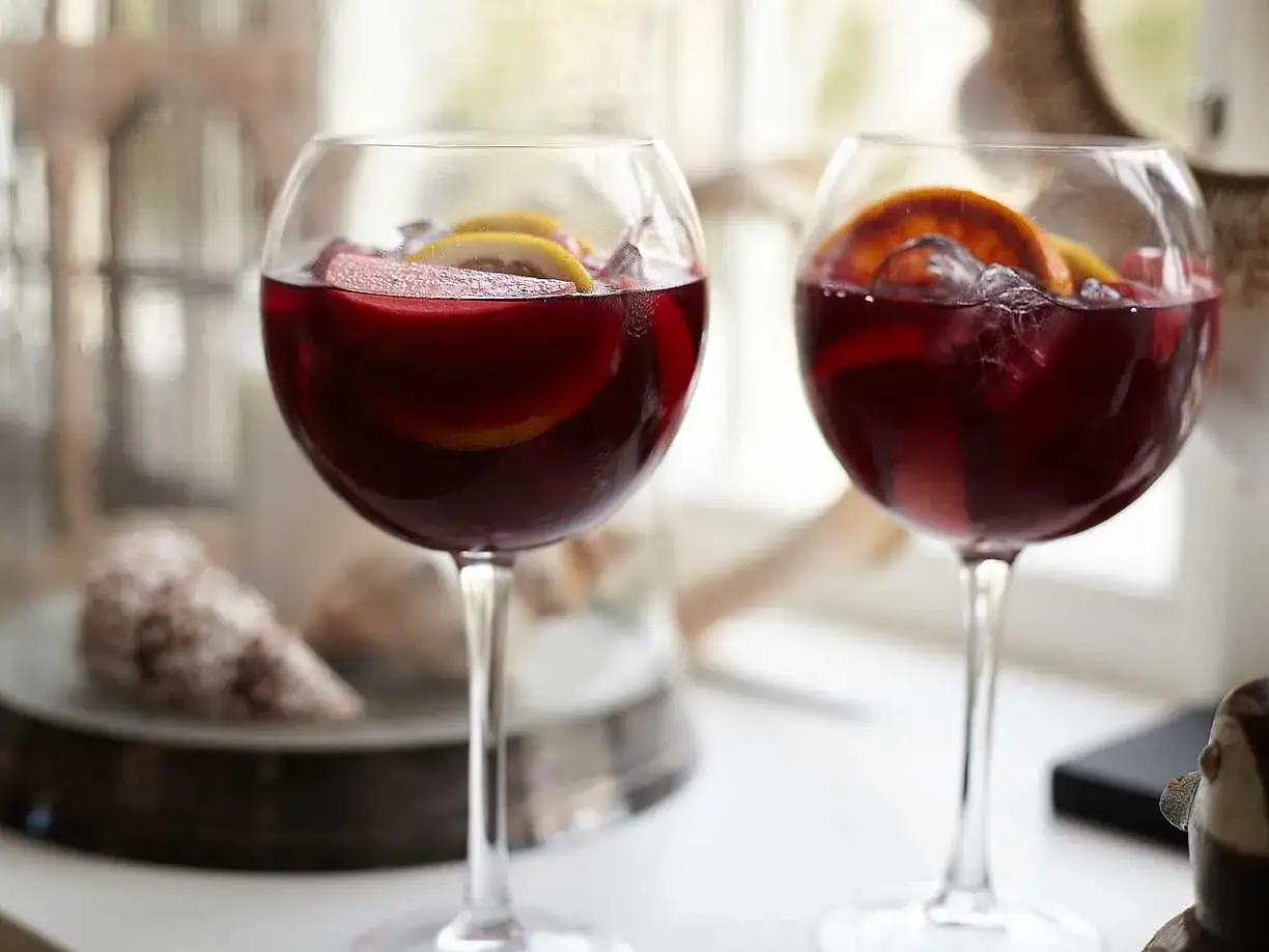 Tv&aring; glas fyllda med r&ouml;d sangria, garnerade med citrusskivor och is. Perfekt f&ouml;r ett somrigt sangria recept.