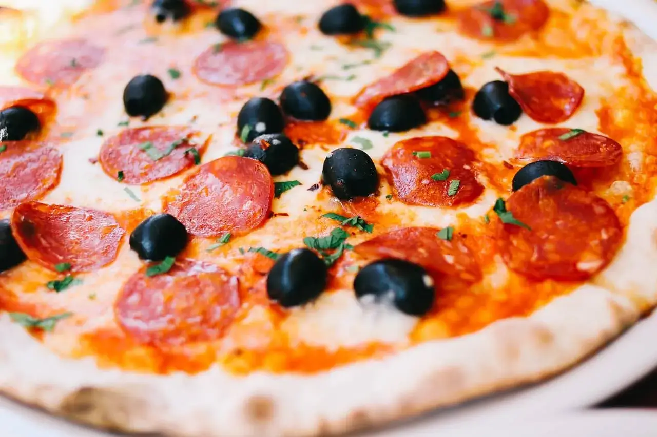 Apetyczna pizza z chrupiącym ciastem, ciągnącym serem, czarnymi oliwkami i pikantnym **peperoni**.