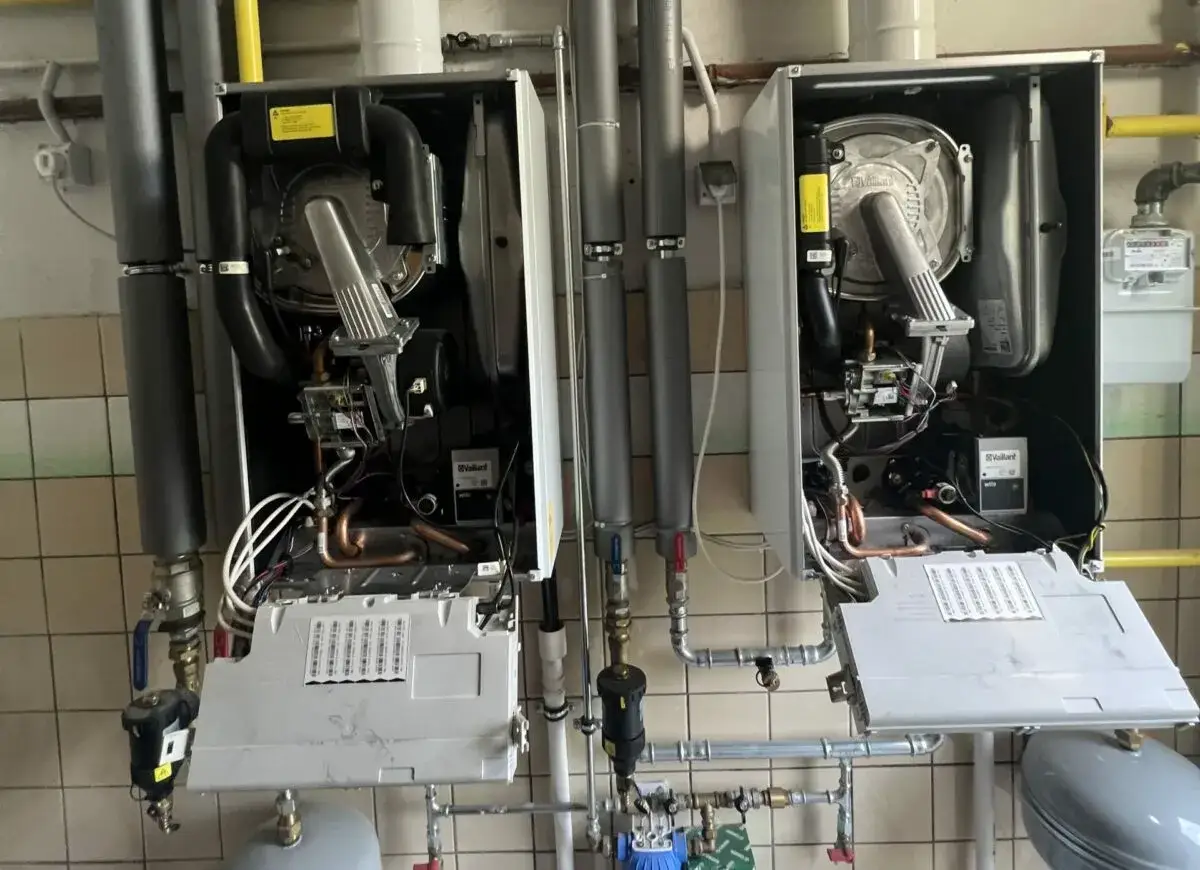 Dwa otwarte kotły gazowe Junkers, widoczne wnętrze z elementami grzewczymi i instalacją hydrauliczną, gotowe do montażu.