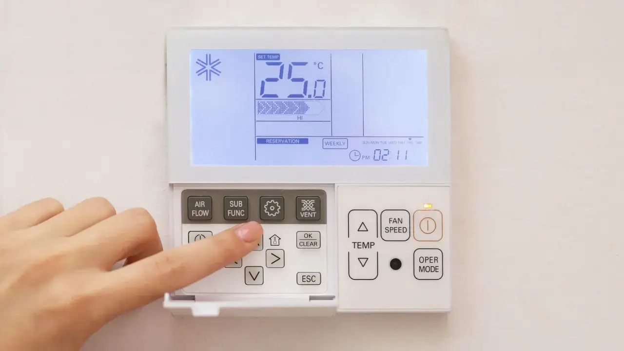Dito si vede un telecomando per condizionatore. La mano preme un tasto, forse per impostare la temperatura o la funzione. Il display mostra 25.0&deg;C.