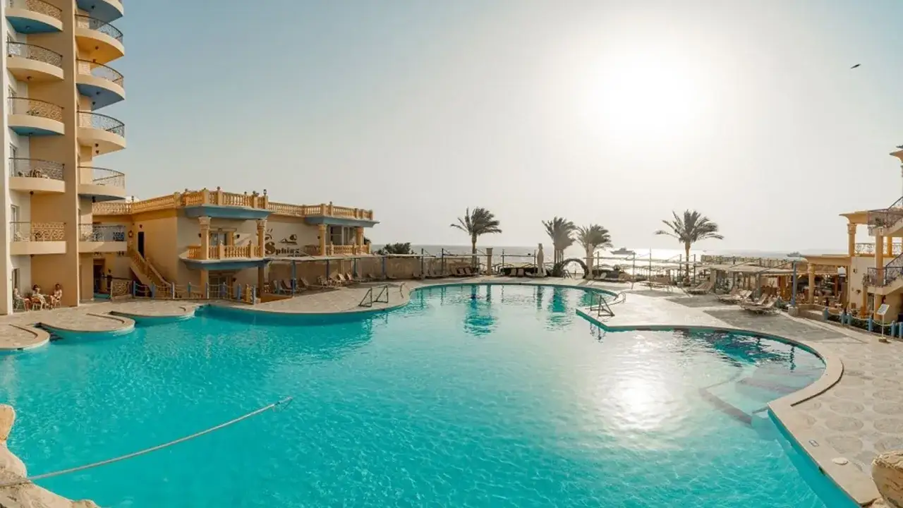 Basen w hotelu King Tut Resort, palmy i morze w tle. Idealne miejsce na wakacje.
