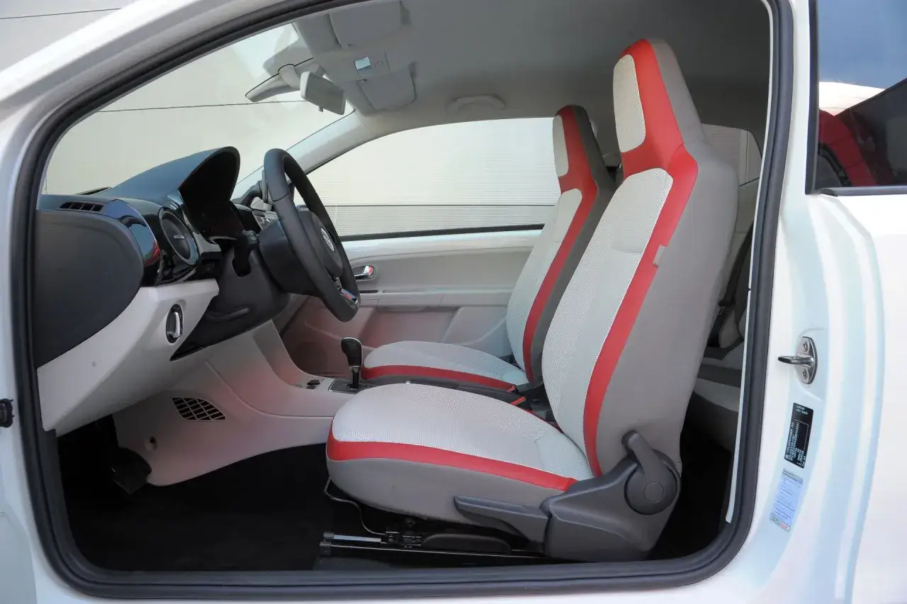 Wnętrze białego volkswagen up! z dwukolorowymi fotelami w odcieniach szarości i czerwieni.