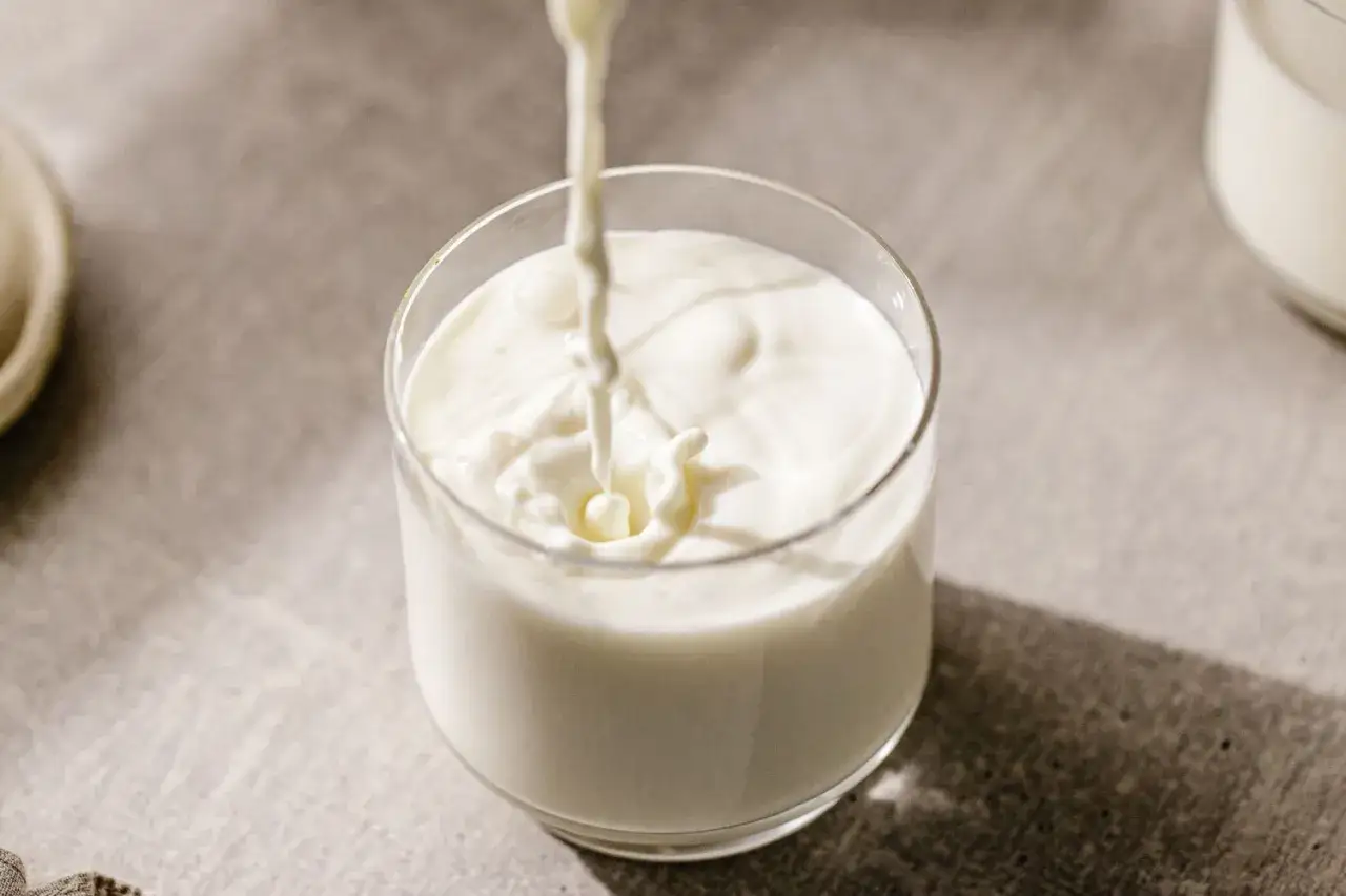 Kefir w szklance, który może pomóc w walce z trądzikiem. Płynny napój tworzy fale na powierzchni.