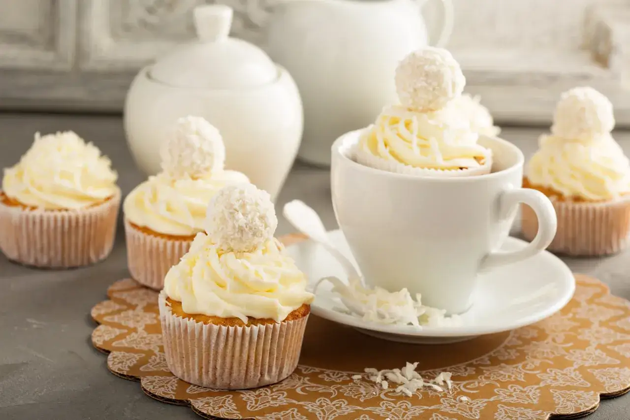 K&ouml;stliche Cupcakes mit Buttercreme-Frosting, inspiriert von einem Buttercreme-Rezept mit Pudding. Verziert mit Kokosraspeln und Schokokugeln.